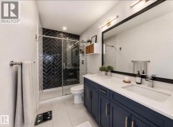 Contemporary bathroom featuring a spacious dual-sink vanity with deep blue cabinetry and light-toned countertops - 