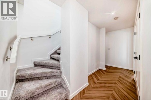 Staircase with gray carpeting, white risers, and a white handrail with brushed nickel supports - 1304 Rutherford Road, Edmonton, AB 