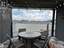 Rooftop patio featuring wood-finish deck tiles, string lighting, and privacy screens - 