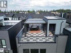 Expansive rooftop deck featuring a checkerboard tile pattern, an integrated pergola, and glass railings - 