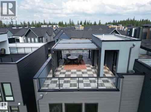Expansive rooftop deck featuring a checkerboard tile pattern, an integrated pergola, and glass railings - 1304 Rutherford Road, Edmonton, AB 