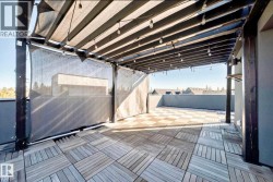 Rooftop patio featuring wood-finish tile flooring, a dark wood pergola with string lighting, and privacy screens - 