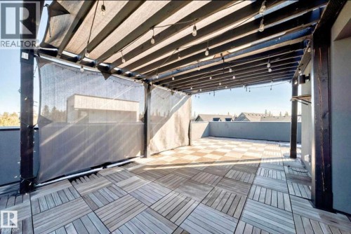 Rooftop patio featuring wood-finish tile flooring, a dark wood pergola with string lighting, and privacy screens - 1304 Rutherford Road, Edmonton, AB 