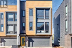 Modern townhome facade featuring a yellow entry door, a two-car garage, and multiple windows across three levels - 