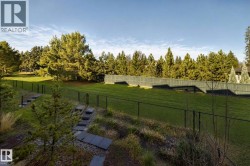 Expansive terraced backyard featuring a manicured lawn, established trees, and a privacy fence - 