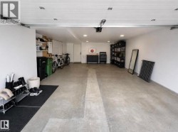 Spacious garage featuring a concrete floor, white painted walls, recessed lighting, and a white paneled ceiling - 