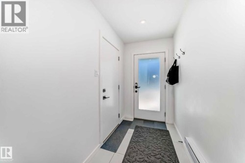 Entryway featuring a white door with frosted glass, recessed lighting, and white tile flooring - 1304 Rutherford Road, Edmonton, AB 