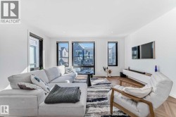 Open-concept living space featuring high ceilings and wood-finish flooring with a herringbone pattern - 
