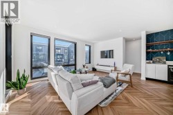 Open-concept living space featuring wood-finish herringbone flooring, extensive natural light, a built-in entertainment unit, recessed lighting, and a custom bar area with patterned wall tile - 