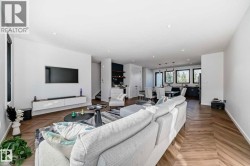 Open-concept living area with herringbone wood-finish flooring, recessed lighting, and a floating media console - 
