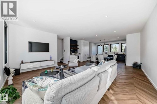 Open-concept living area with herringbone wood-finish flooring, recessed lighting, and a floating media console - 1304 Rutherford Road, Edmonton, AB 