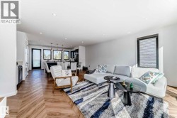 Open-concept living area featuring wood-finish flooring in a herringbone pattern and recessed lighting - 