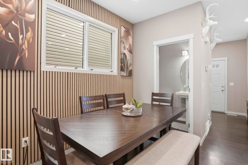 Dining area featuring a wood-panel accent wall, a double window with horizontal blinds, and dark wood-finish flooring - 4320 Annett Common, Edmonton, AB - Indoor Photo Showing Dining Room