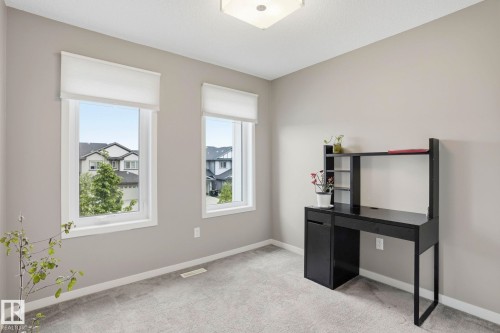 Carpeted room featuring two white-framed windows with roller blinds, a flush-mount ceiling light, and light gray wall paint - 4320 Annett Common, Edmonton, AB - Indoor Photo Showing Other Room