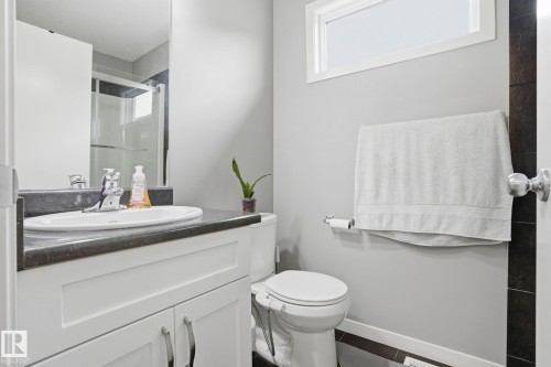 Bathroom featuring a white vanity with dark countertop, undermount sink, and chrome faucet - 4320 Annett Common, Edmonton, AB - Indoor Photo Showing Bathroom