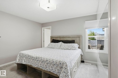 Spacious bedroom with light gray walls, plush gray carpet, a contemporary flush-mount ceiling light, and a white-framed window - 4320 Annett Common, Edmonton, AB - Indoor Photo Showing Bedroom