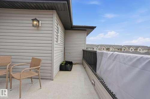 Exterior balcony featuring light gray siding, dark soffits, a black metal railing, and a wall-mounted outdoor light fixture - 4320 Annett Common, Edmonton, AB - Outdoor With Exterior