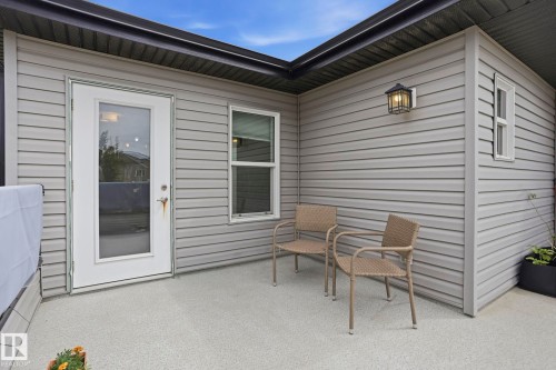 Private outdoor patio featuring a full-light exterior door, durable composite decking, and a contemporary wall-mounted lantern - 4320 Annett Common, Edmonton, AB - Outdoor With Exterior