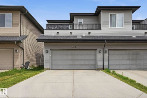 Concrete driveway leading to a two-car garage with overhead doors - 4320 Annett Common, Edmonton, AB - Outdoor With Exterior