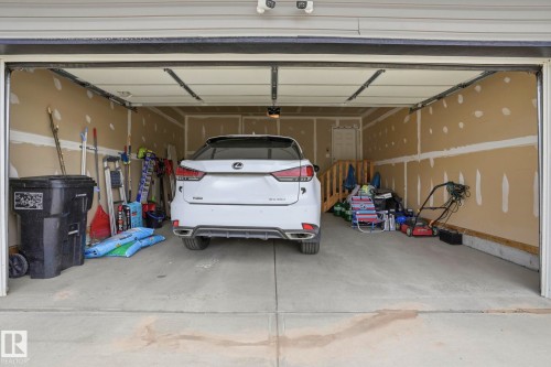 Two-car garage featuring a concrete floor, unpainted drywall, and a wooden staircase - 4320 Annett Common, Edmonton, AB - Indoor Photo Showing Garage