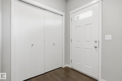 Entryway featuring a paneled door with transom window, bifold closet doors, light gray wall paint, white trim, and wood-finish flooring - 4320 Annett Common, Edmonton, AB - Indoor Photo Showing Other Room