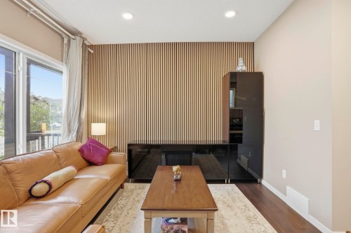 Living area featuring a slatted wood accent wall, recessed ceiling lighting, and wood-finish flooring - 4320 Annett Common, Edmonton, AB - Indoor Photo Showing Other Room