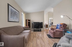 Spacious living area featuring wood-finish flooring and vaulted ceilings - 