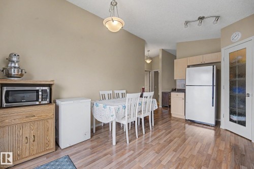 Dining area featuring wood-finish flooring, a contemporary ceiling fixture, and direct access to the kitchen - 19039 47 Avenue, Edmonton, AB 