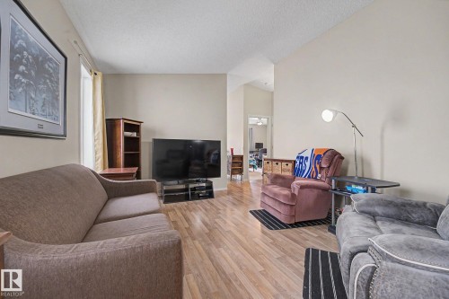 Spacious living area featuring wood-finish flooring, neutral wall tones, and vaulted ceilings - 19039 47 Avenue, Edmonton, AB 