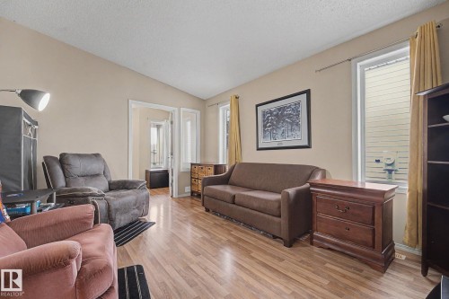 Living area featuring wood-finish flooring, vaulted ceilings, and light-toned wall paint - 19039 47 Avenue, Edmonton, AB 