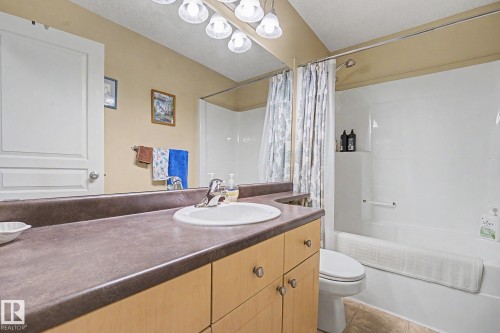 Bathroom featuring a light wood-finish vanity with a dark countertop, white drop-in sink, and chrome faucet - 19039 47 Avenue, Edmonton, AB 