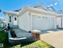 Light gray siding exterior with a matching garage door featuring upper window panels - 19039 47 Avenue, Edmonton, AB 