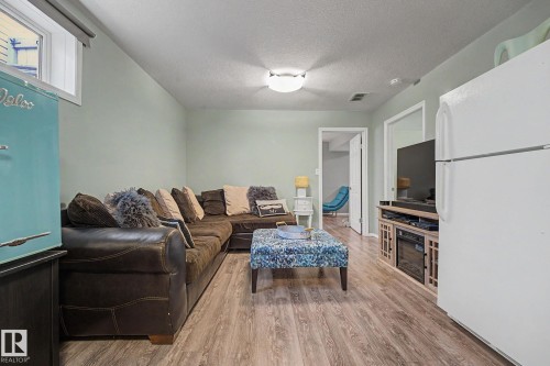 Living area featuring wood-finish flooring, a neutral wall color, recessed lighting, a ceiling-mounted light fixture, and a built-in media console - 19039 47 Avenue, Edmonton, AB 