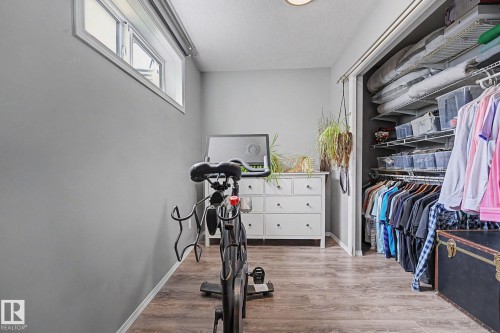 Room featuring wood-finish flooring, a functional window, and a built-in closet with wire shelving and hanging rods - 19039 47 Avenue, Edmonton, AB 