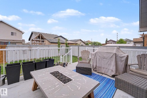 Outdoor deck featuring a built-in fire pit, white railing, and a slatted privacy fence - 19039 47 Avenue, Edmonton, AB 