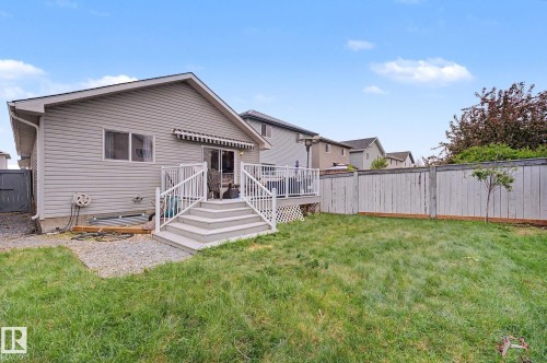 Spacious backyard featuring a multi-level deck with white railings, a sliding glass door entry, an attached awning, and a wooden privacy fence - 19039 47 Avenue, Edmonton, AB 
