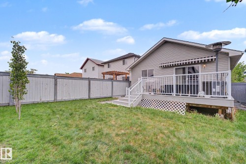 Expansive backyard featuring a manicured lawn, a full privacy fence, and a raised composite deck with white railings and a retractable awning - 19039 47 Avenue, Edmonton, AB 