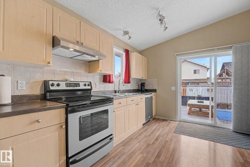 Kitchen featuring light wood-finish cabinetry, stainless steel appliances, and a tiled backsplash - 19039 47 Avenue, Edmonton, AB 