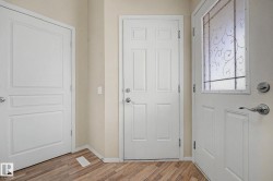 Entryway featuring a decorative glass panel door, wood-finish flooring, and white trim - 