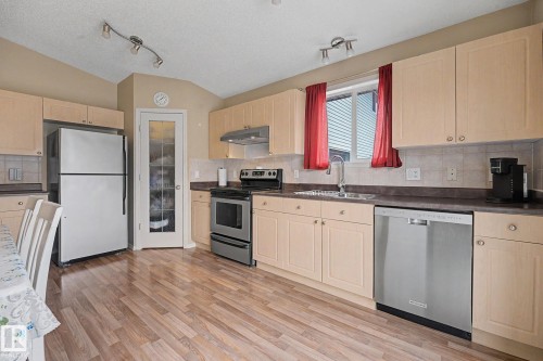 Kitchen featuring wood-finish flooring, light-toned cabinetry, stainless steel appliances, and track lighting - 19039 47 Avenue, Edmonton, AB 
