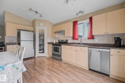 Kitchen featuring wood-finish flooring, ample cabinetry, stainless steel appliances, and a pantry with a glass-paneled door - 