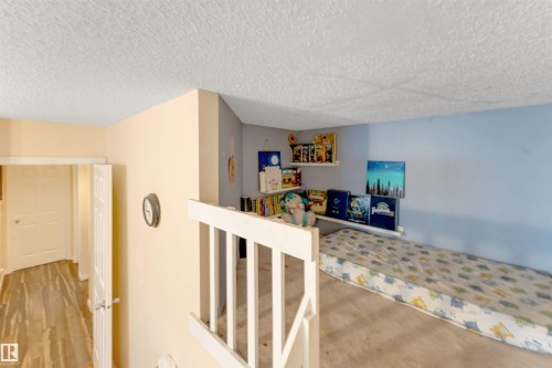 Loft space featuring a light blue accent wall, recessed shelving, and a textured ceiling - 312 Beringer Crescent, Edmonton, AB 