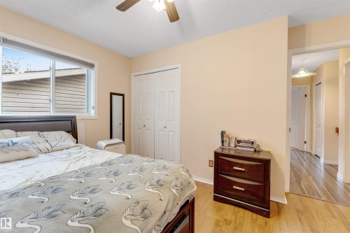 Bedroom featuring wood-finish flooring, a ceiling fan, and a window with white trim - 312 Beringer Crescent, Edmonton, AB 