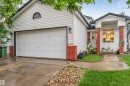 White vinyl siding exterior with an attached garage, brick accents, and a covered entry - 312 Beringer Crescent, Edmonton, AB 