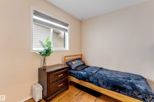 Bright interior space featuring wood-finish flooring, a white-framed window with a roller blind, and light-toned walls - 312 Beringer Crescent, Edmonton, AB 