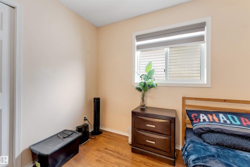 Room featuring wood-finish flooring, a window with horizontal blinds and a roller shade, and light-toned walls - 312 Beringer Crescent, Edmonton, AB 