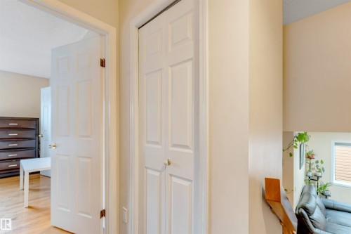 Hallway featuring light-toned walls, white paneled doors, and wood-finish flooring - 312 Beringer Crescent, Edmonton, AB 