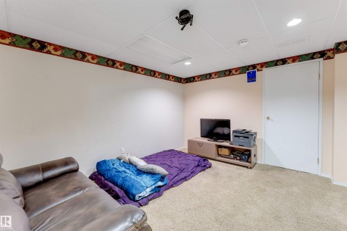 Carpeted room featuring a drop ceiling with recessed lighting and a wall-mounted projector - 312 Beringer Crescent, Edmonton, AB 