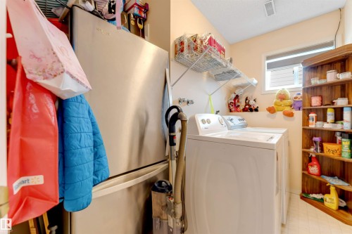 Laundry area featuring a top-load washing machine, a wall-mounted wire shelf, a window, and a built-in wooden corner shelving unit - 312 Beringer Crescent, Edmonton, AB 