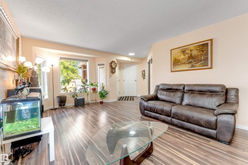 Spacious living area featuring wood-finish flooring, a bright bay window, and a white entry door - 312 Beringer Crescent, Edmonton, AB 